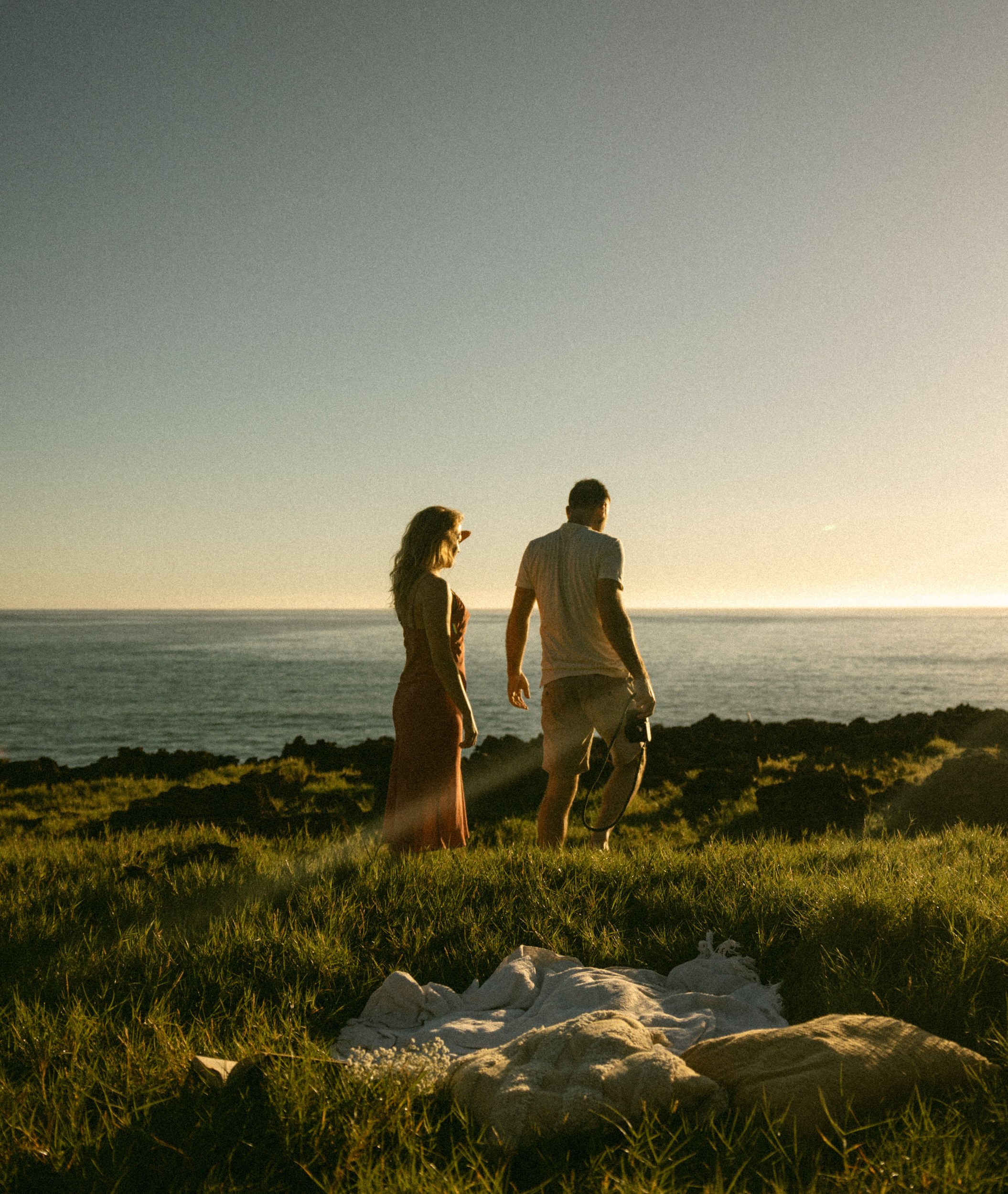 Your hosts walking together on a rocky Hawaiian coastline at golden hour